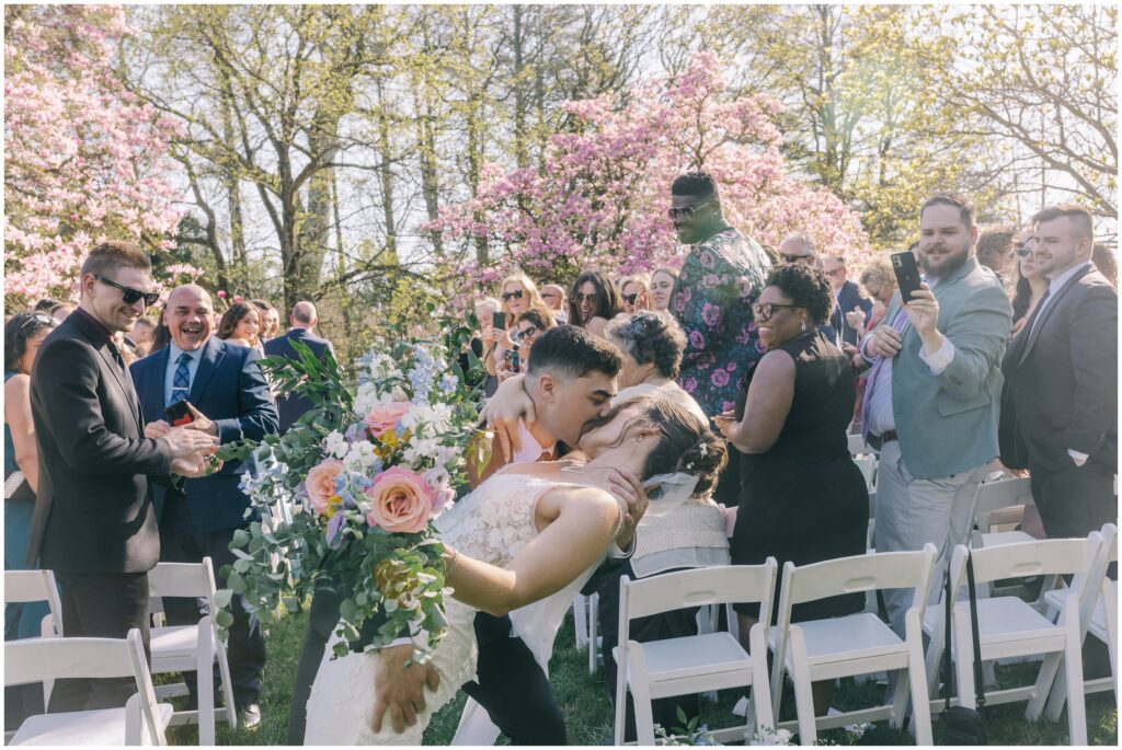 Dip kiss while walking down the aisle during springtime wedding
