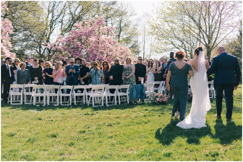 Bride walking down the aisle on a beautiful spring day from behind.