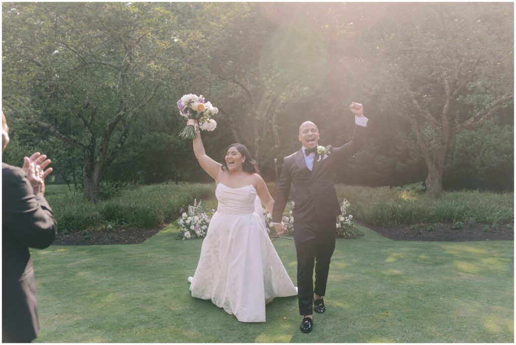 Newlyweds cheering as they walk back down the aisle at the brantwyn estate 