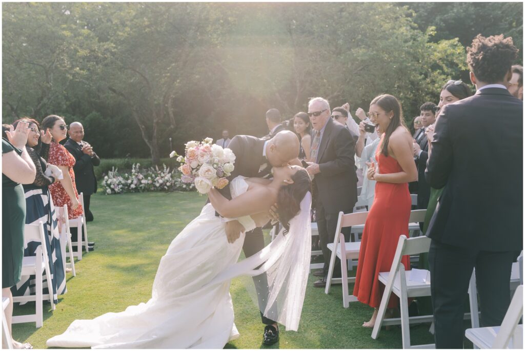 groom dips bride for a kiss while walking down the aisle at the Brantwyn Estate 