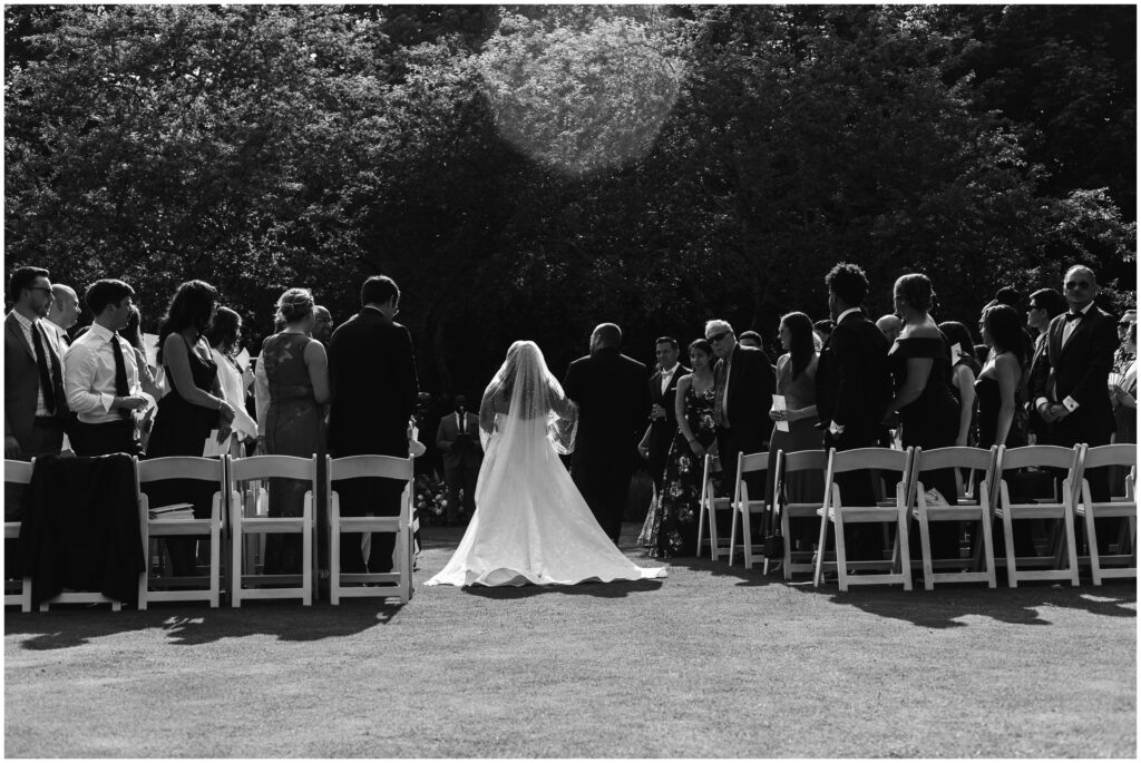 Black and white editorial image of bride walking down isle